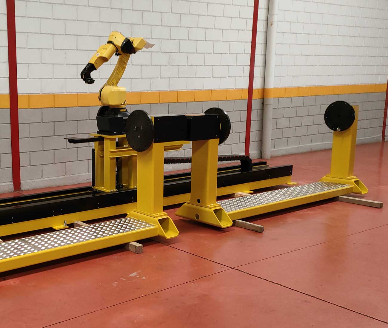 Célula soldadura mesa paralela tipo torno con robot sobre track suelo